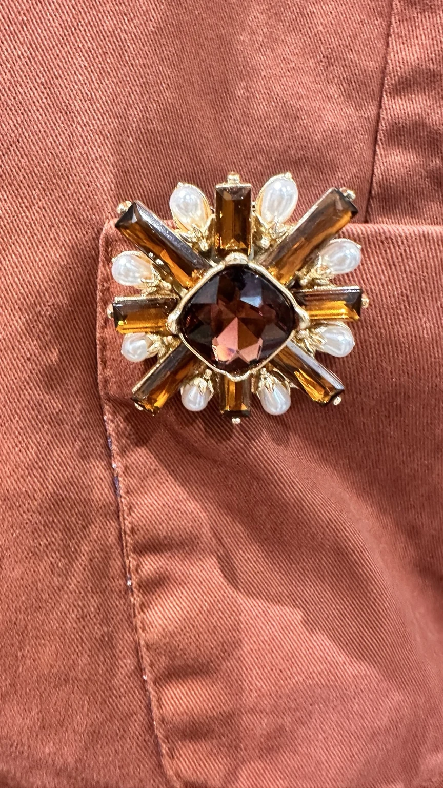 Broche aux pierres ambrées et perles claires sur un tissu terracotta