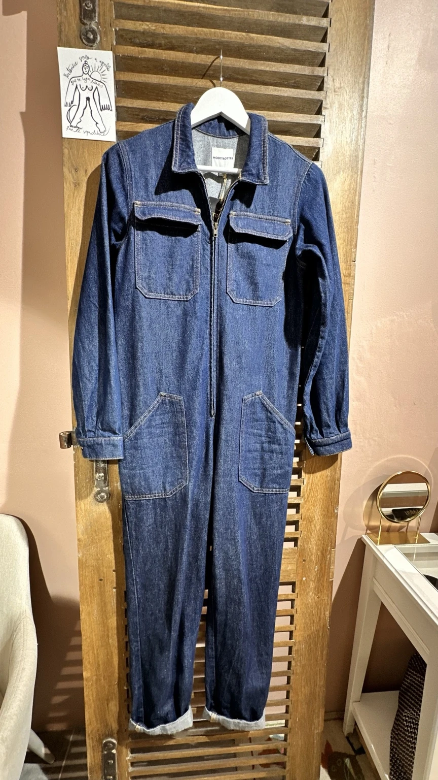 Combinaison en jean bleu à fermeture zippée, présentée sur un cintre en boutique