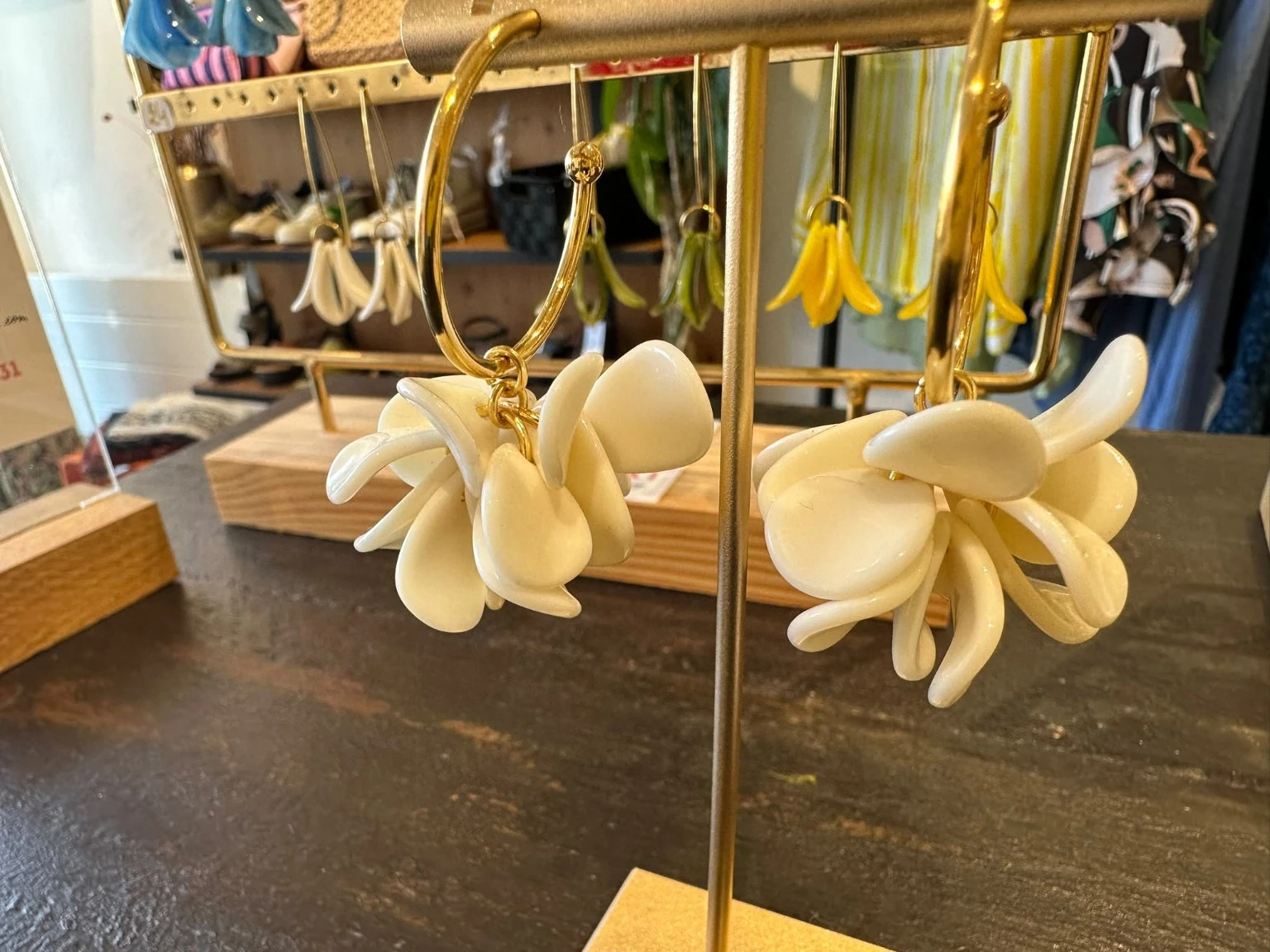 Boucles d’oreilles Ola Pampa écrues sur des créoles dorées, présentées en boutique